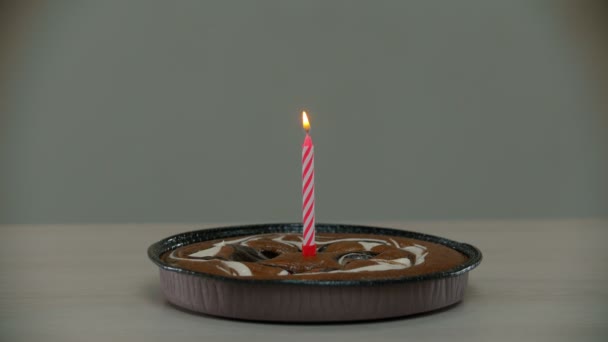 Samotny tort ze świecą stoi na stole — Wideo stockowe