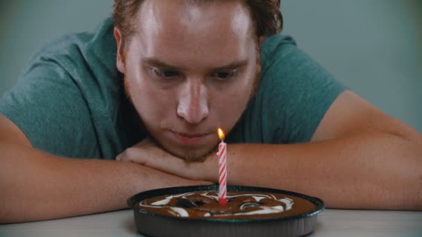 男が誕生日ケーキの上でろうそくを吹き消している — ストック動画