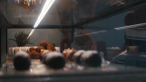 Junge Mädchen schauen sich die Süßigkeiten in der Bäckerei an — Stockvideo