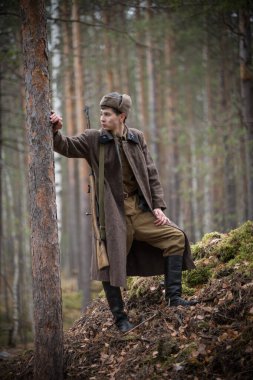 2. Dünya Savaşı 'ndan bir asker ağacın yanında duruyor ve soluna bakıyor.