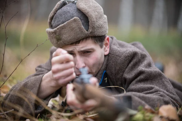 Voják druhé světové války nabíjí pušku, zatímco leží na bitevním poli. — Stock fotografie