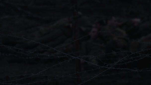 Vojáci sedí v noci v zákopu za drátěnou žehličkou — Stock video