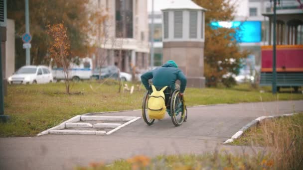 Gehandicapte man in rolstoel doet mislukte poging om zijn rolstoel over een helling te sturen — Stockvideo