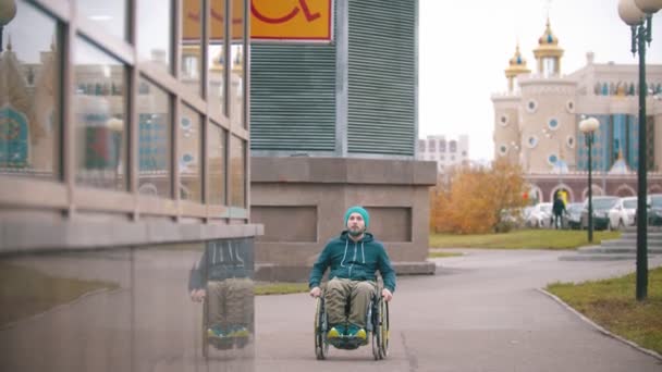 Handikappad man i rullstol ser skylten "Handikappad" och rör sig mot den speciella platsen — Stockvideo