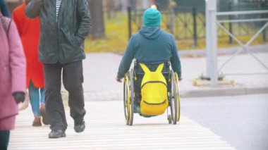 Tekerlekli sandalyedeki engelli adam gündüz vakti karşıdan karşıya geçiyor.