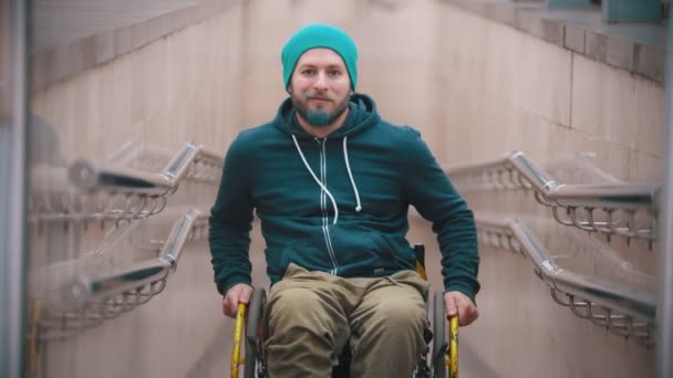 Homme handicapé en fauteuil roulant sourire et montrant les possibilités de son fauteuil roulant se déplaçant sur les côtés et se penchant sur les roues arrière — Video