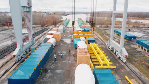 Puerto de carga: una gran grúa industrial que carga la carga en el transporte de mercancías sobre raíles — Vídeo de stock