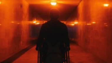 Akşamları boş alt geçitte tekerlekli sandalyede oturan engelli bir adam.