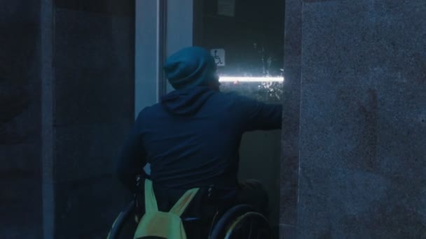 Homem com deficiência em cadeira de rodas usando um elevador especial para pessoas com deficiência para se levantar da travessia subterrânea à noite — Vídeo de Stock