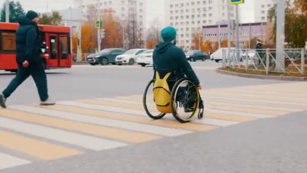 Hombre discapacitado en silla de ruedas cruzando la calle en la ciudad — Vídeos de Stock