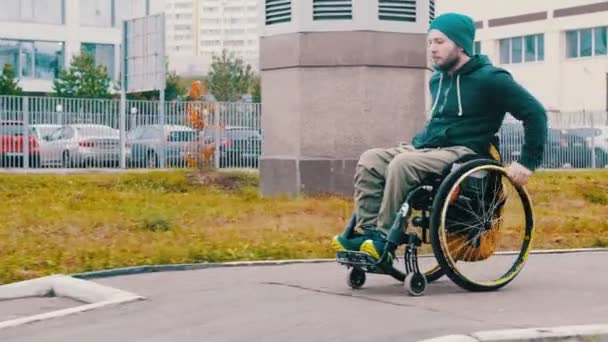 Инвалид в инвалидной коляске спускается по пандусу на улице — стоковое видео