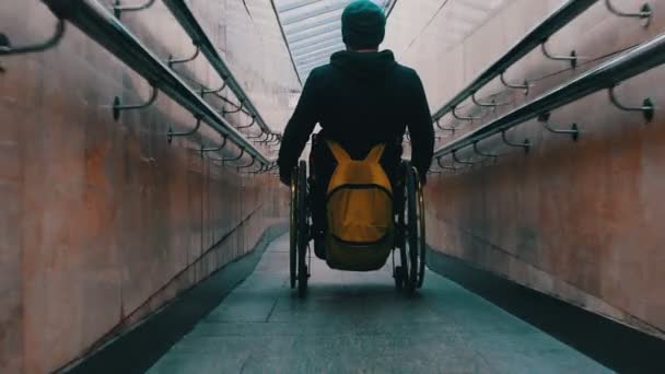 Инвалид в инвалидной коляске спускается по длинной специальной рампе в метро — стоковое видео