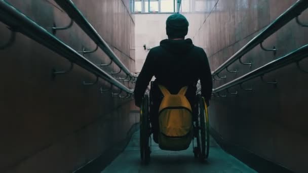 Hombre discapacitado en silla de ruedas bajando por la larga rampa en el metro — Vídeo de stock