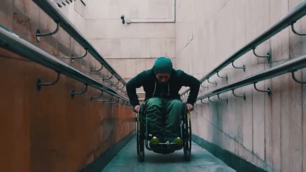 Hombre discapacitado en silla de ruedas levantándose en la larga rampa especial a veces apoyado en la barandilla — Vídeos de Stock