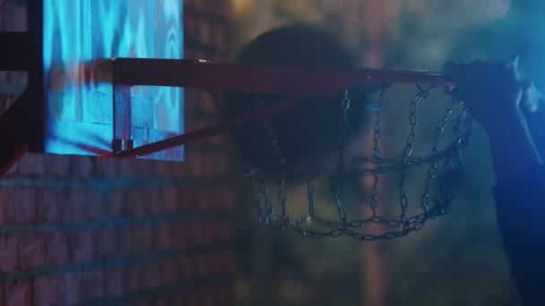 Basketbol topunun gece açık hava oyun sahasında potaya girmesi - smaç. — Stok video