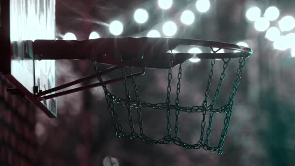 Bola de basquete entrando no aro no playground ao ar livre à noite em luzes brilhantes — Vídeo de Stock