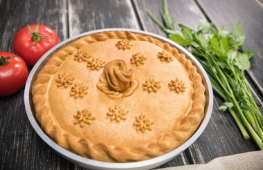 Üstünde yenilebilir süslemeler olan tatlı patates turtası. Yanında yeşiller ve domatesler.