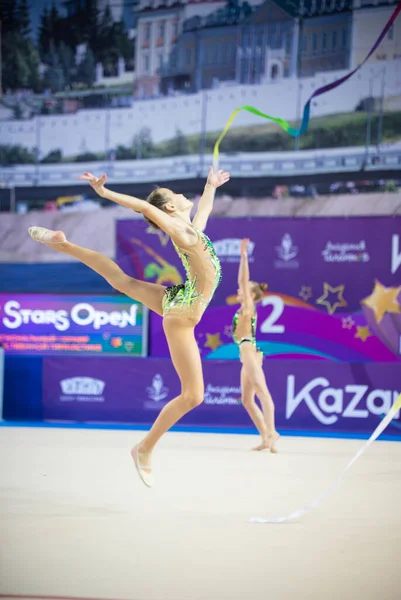 12-03-2020 RUSSIA, KAZAN: 밝은 녹색 수영복을 입고 체조 토너먼트에서 핑크 리본으로 공연하는 소녀 — 스톡 사진