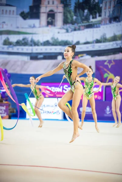 12-03-2020 KAZAN, RÚSSIA: grupo de meninas adolescentes ginastas em trajes de natação saltar enquanto executa seu número com fitas coloridas no torneio de ginástica — Fotografia de Stock