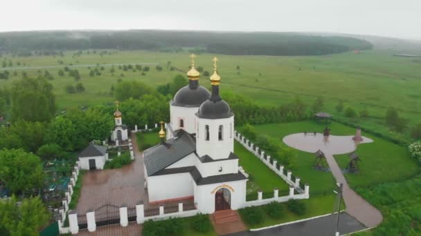 Keresztény templom a faluban és temető az eső alatt — Stock videók