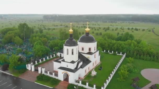 Christian church in the middle of the field and cemetery under the rain — Stock Video