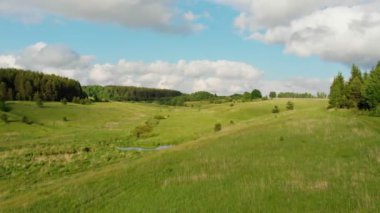 Yeşil açık arazi ve bulutlu mavi gökyüzü