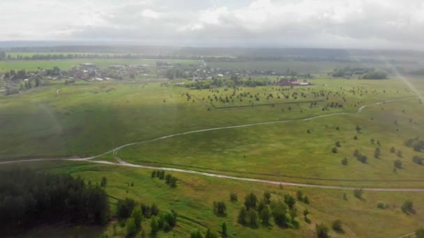 Zelené otevřené pole a vesnice pod deštěm — Stock video