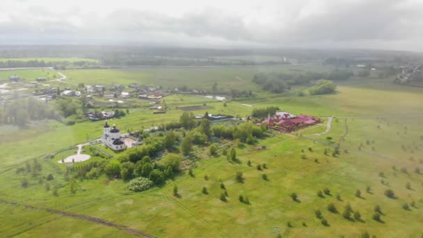 Zelené otevřené pole a vesnice a kostel pod deštěm — Stock video