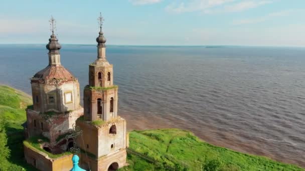 Vieille église chrétienne en brique délabrée avec dômes noirs près de la rivière — Video