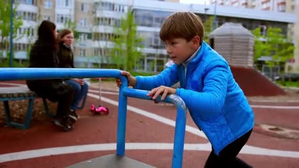 Un petit garçon jouant sur l'aire de jeux extérieure — Video