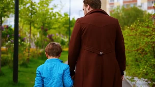 Joven y su hermano pequeño caminando en la plaza y pasando tiempo juntos — Vídeo de stock