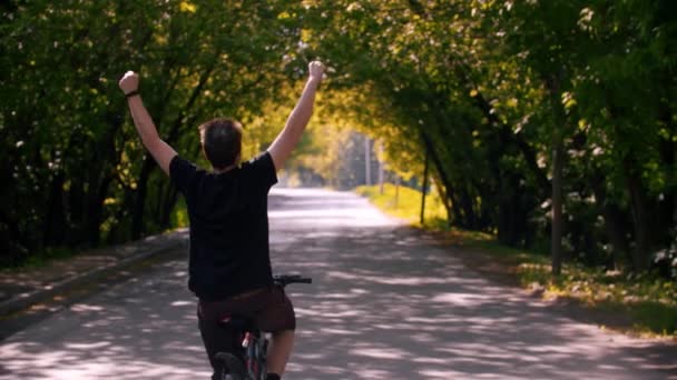 Jongeman op een fiets met opgeheven handen — Stockvideo