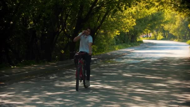 Junger Mann fährt Fahrrad und telefoniert - beinahe gestürzt — Stockvideo