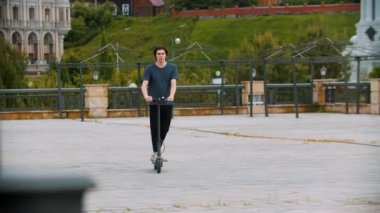 Parkta elektrikli scooter kullanan yakışıklı bir genç.