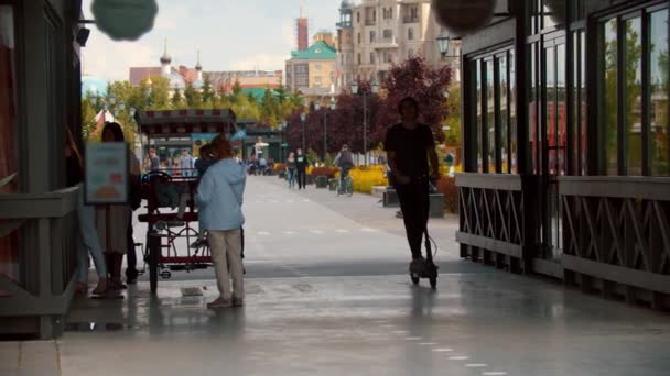 Ung stilig man rider en elektrisk skoter på upptagen gata — Stockvideo