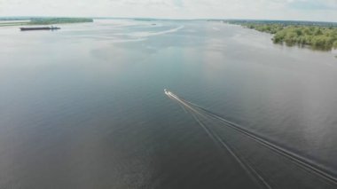Nehirde yüzen sürat teknesi ve mavna geçiyor - sudaki yeşil adalar