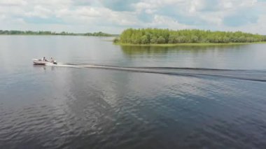 İki adam nehirde motorlu tekne sürüyor.