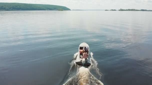 Dos hombres a caballo en barco a motor en el río a la luz del día - islas verdes en el agua — Vídeos de Stock