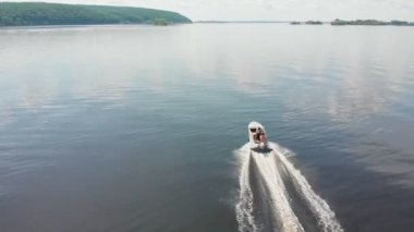 Gündüz vakti nehirde beyaz motorlu tekneye binen iki adam. Suda yeşil adalar.