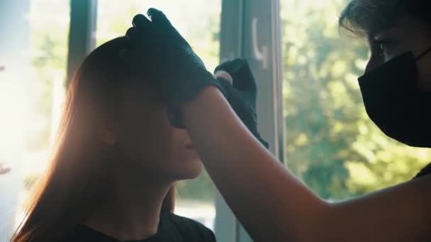Mujer joven cosmetólogo borra modelos cejas — Vídeo de stock
