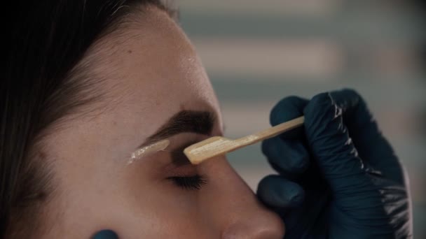 Brow master tillämpa vax på ögonbrynet ben ung kvinna — Stockvideo