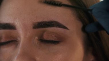 Brow ustası renkli kaşlarını fırçalıyor.