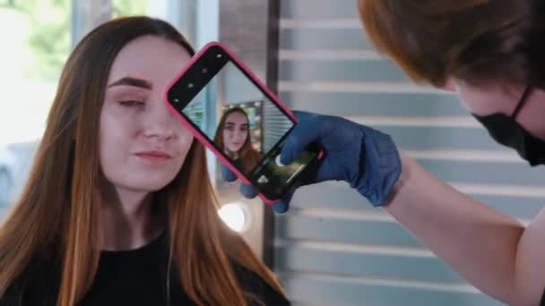 Brauenmeisterin fotografiert auf ihrem Handy das fertige Ergebnis der Brauenfärbung — Stockvideo