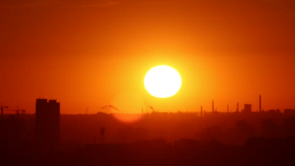 La brillante luz del sol naranja brilla sobre la ciudad y el sol se pone al atardecer - obra industrial — Vídeos de Stock