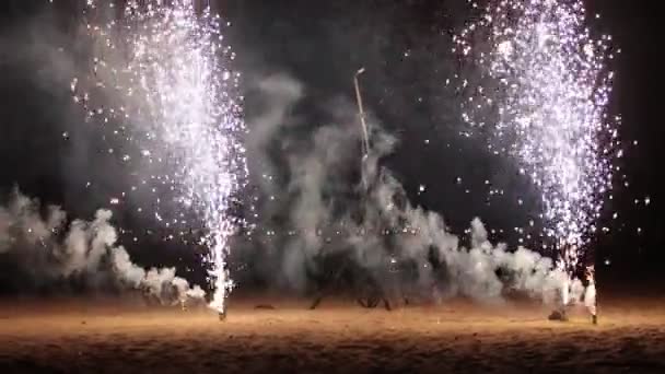 Dois pequenos fogos de artifício brancos queimando e explodindo - espalha brilhos na praia — Vídeo de Stock