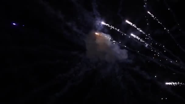 Coloridos fuegos artificiales explotando en el aire por la noche y dejando las huellas de humo — Vídeos de Stock