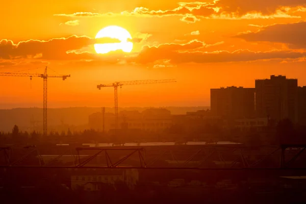Bright orange sunrise shines on the industrial construction site