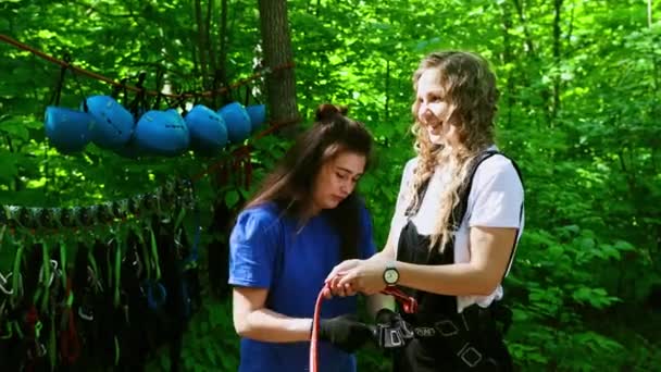 Touw avontuur - een jonge vrouw instructeur zet op de verzekering hangers op de taille van een vrouw — Stockvideo