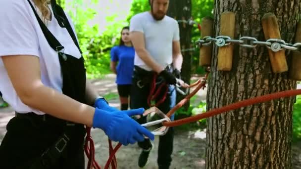 Seil-Abenteuer - ein Paar bewegt sich mit dem Versicherungsgurt am Seil auf die Brücke — Stockvideo