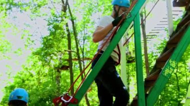 İp macerası - kadın ve erkek macera alanındaki asma köprüye doğru yürüyorlar